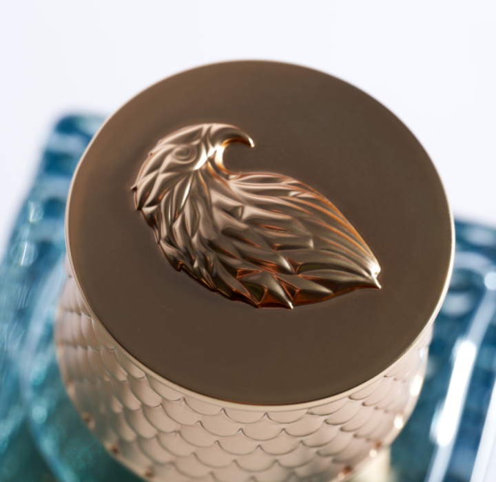 Gros plan vu du dessus d'un parfum Plisson 1808 au couvercle doré satiné, orné d'un aigle sculpté en relief.