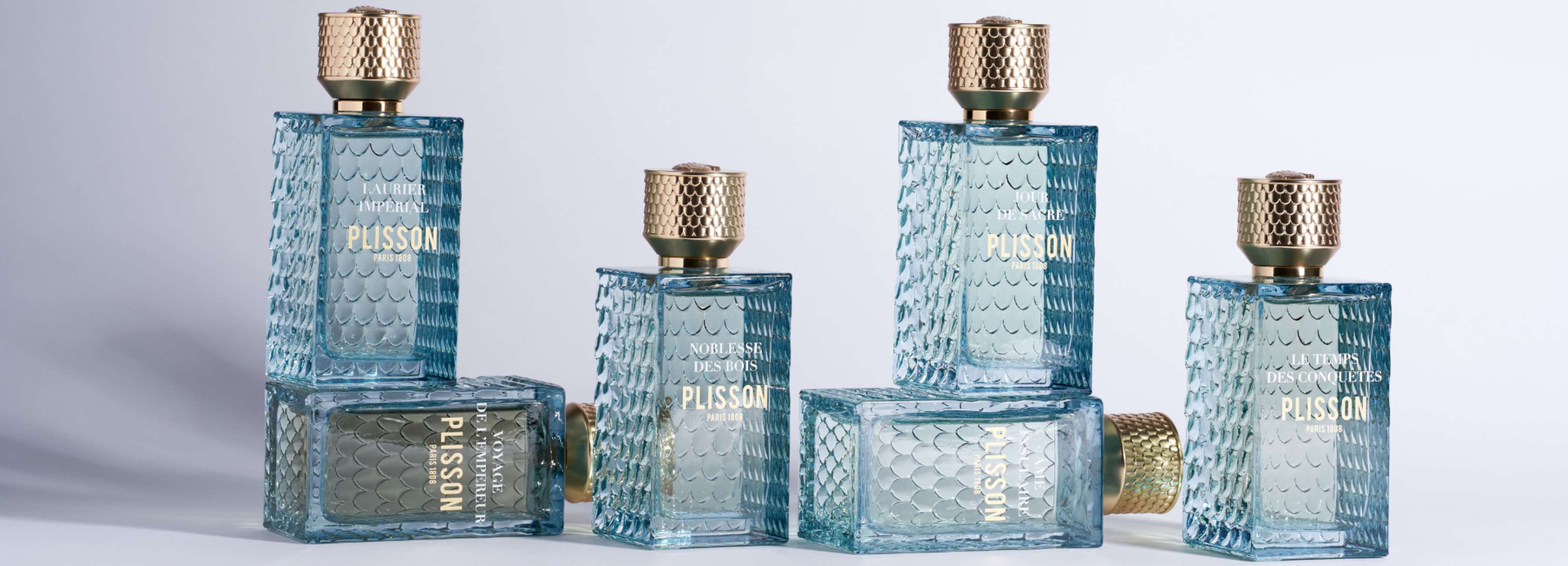 Collection de parfums Plisson 1808 Paris en flacons bleus texturés avec bouchons dorés – Laurier Impérial, Noblesse des Bois, Le Temps des Conquêtes