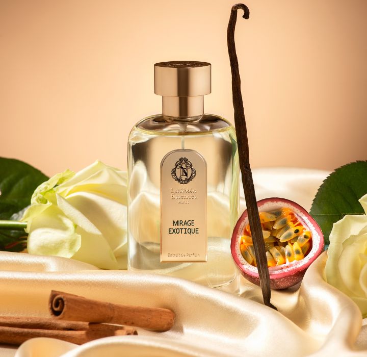 Flacon de parfum Mirage Exotique. Le flacon est posé sur de la soie couleur crème, entouré de vanille, cannelle et fruit de la passion.