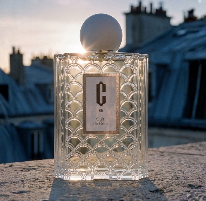 Perfume bottle of Cray’s Cuir de Fleur placed on a terrace, with the rooftops of Paris in the background.