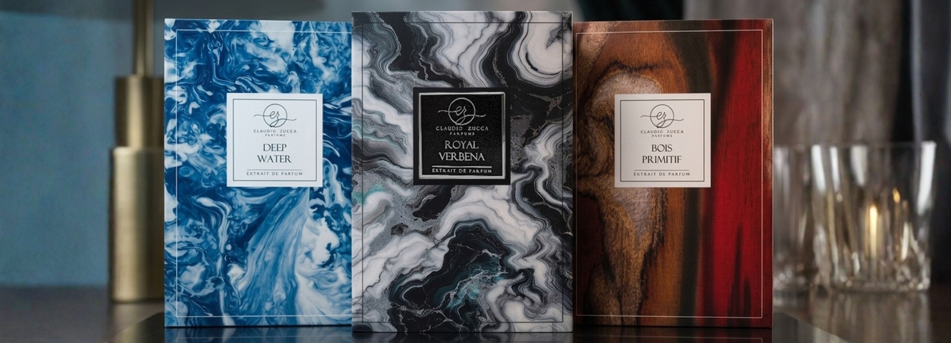 Tres estuches de extracto de perfume de Claudio Zucca Parfums: Deep Water, Royal Verbena y Bois Primitif con diseños marmoleados.
