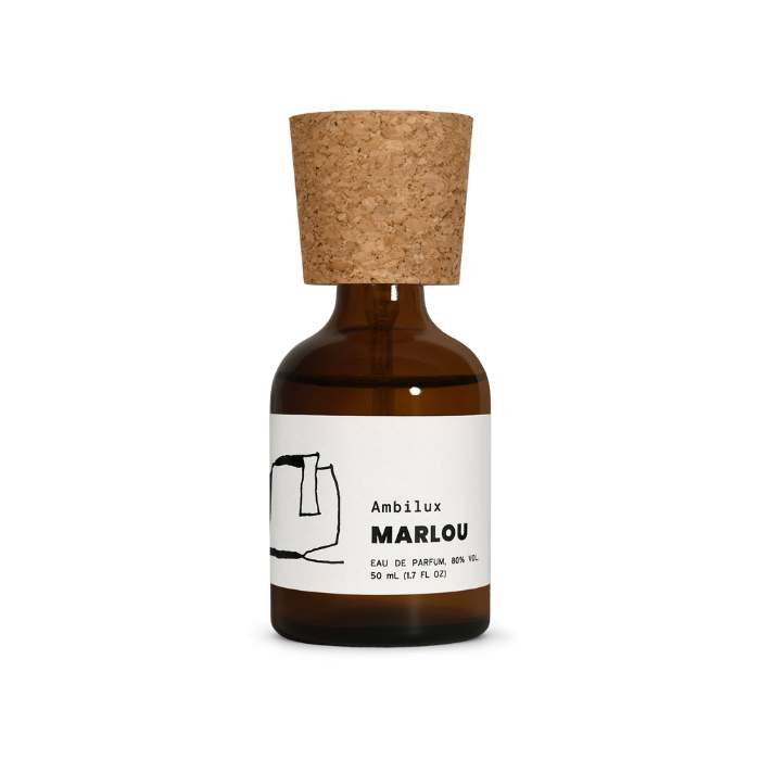 L'image montre un flacon de parfum de la marque Electimuss, mis en valeur par un éclairage coloré. Le flacon a une forme élégante, avec une base rouge et un bouchon doré brillant. À l'arrière-plan, des panneaux de verre colorés dans des tons de jaune, violet et rouge créent un effet de lumière vibrante et réfléchissante. Le design luxueux du flacon, avec un médaillon décoratif, est accentué par les reflets des couleurs, ajoutant une dimension artistique à la composition.