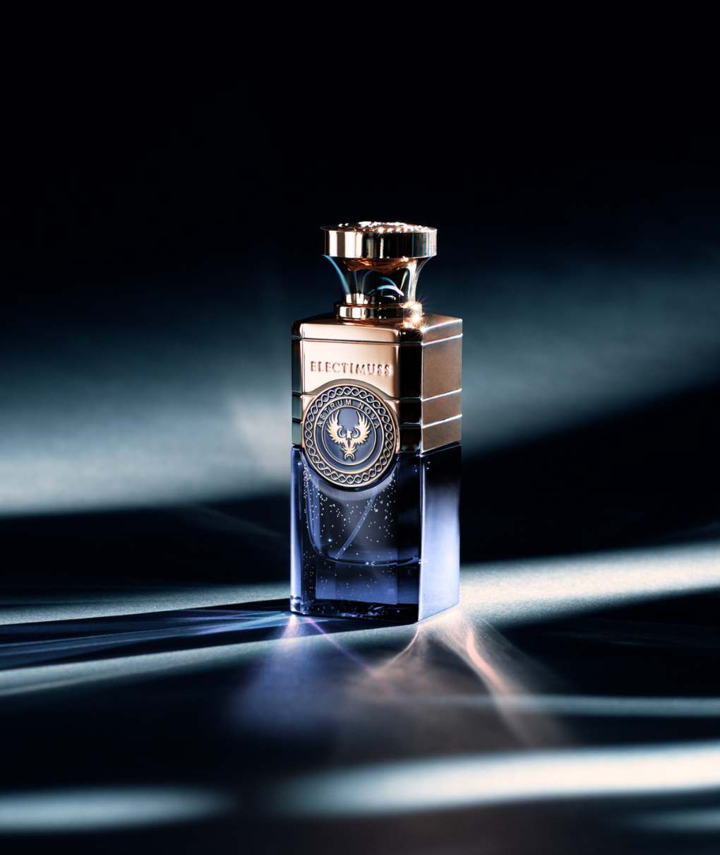 De afbeelding toont een flesje Astrum Nova parfum, iets opzij geplaatst. Het flesje is rechthoekig met afgeronde hoeken. De hoofdkleur is diep, rijk blauw.

Op de voorkant van de flacon zit een gouden medaillon met een cirkelvormig patroon en inscriptie, wat een vleugje elegantie toevoegt. De dop is ook goud, met een geraffineerd ontwerp.

Licht speelt op de fles en creëert reflecties en schaduwen die een indruk van diepte geven. Lichtstralen strekken zich uit rond de fles en creëren een mysterieuze en fascinerende sfeer. De achtergrond is wazig en donker, waardoor de fles wordt benadrukt en haar allure wordt geaccentueerd.
