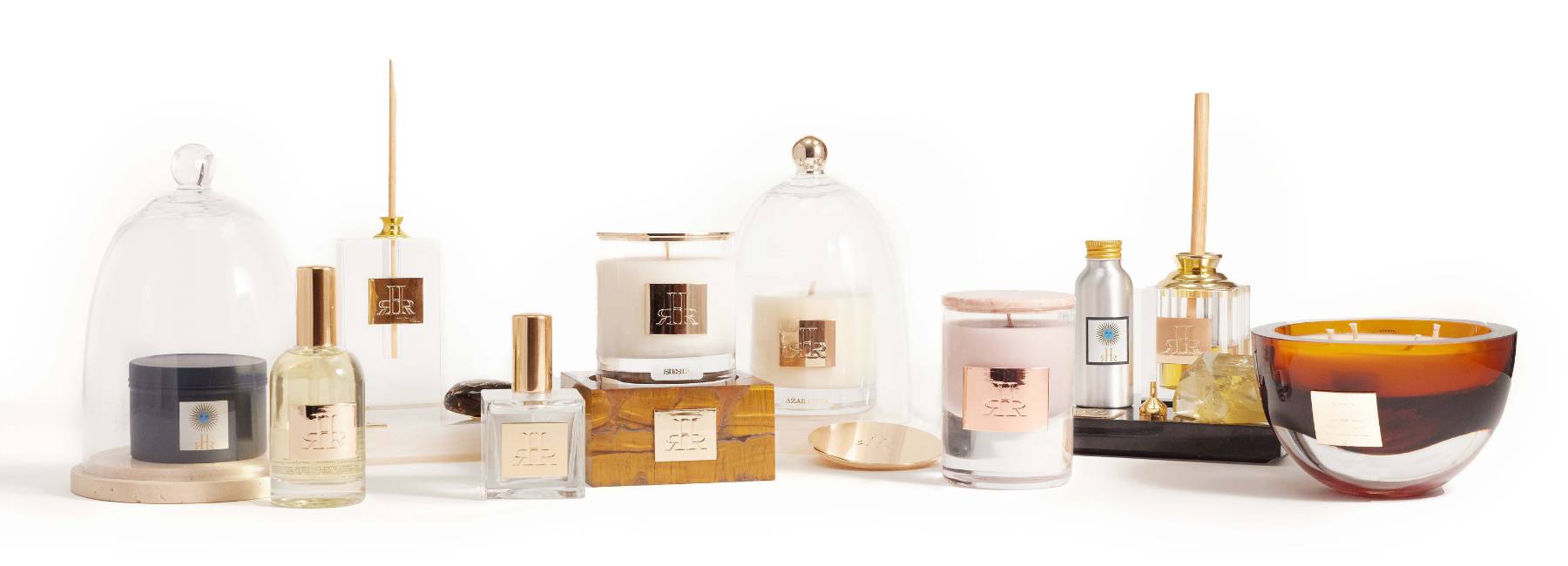 Une collection de bougies et de parfums de la marque RHR Luxury présentés sur une surface blanche, comprenant des bougies sous cloche et dans des contenants variés.