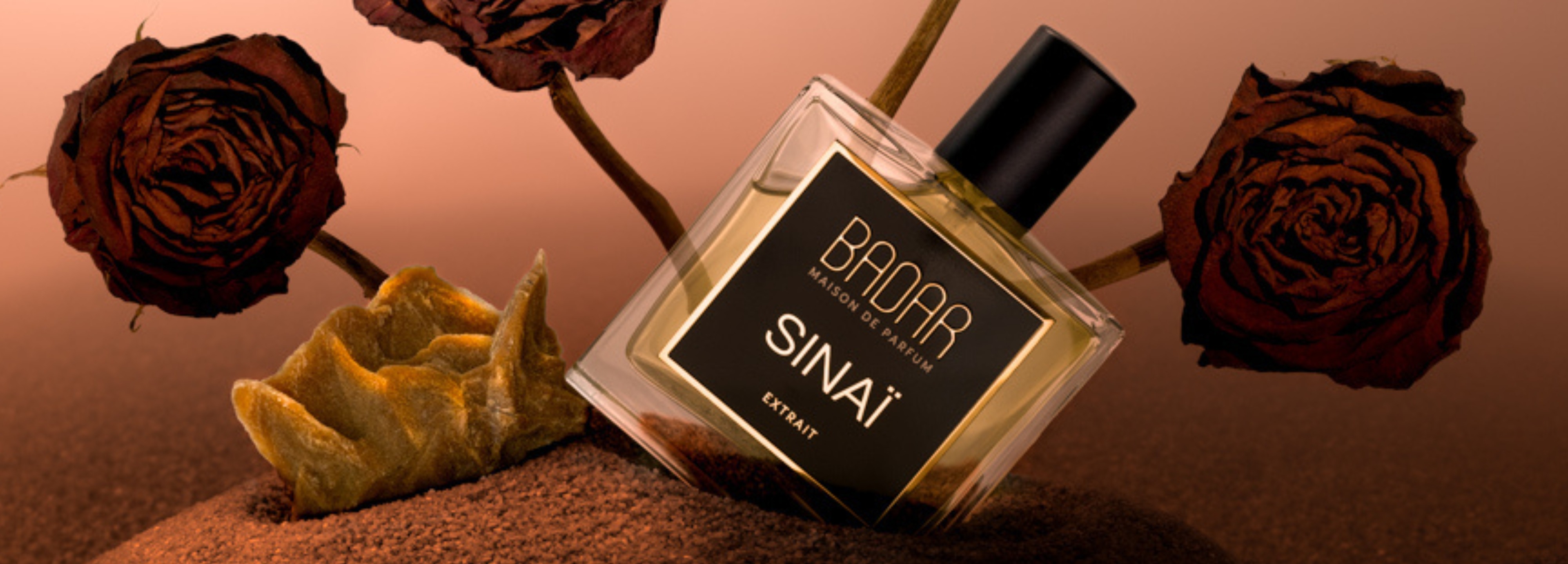 Badar Sinaï Extrait de Parfum - nis parfumflesje op zand, omringd door gedroogde rozen