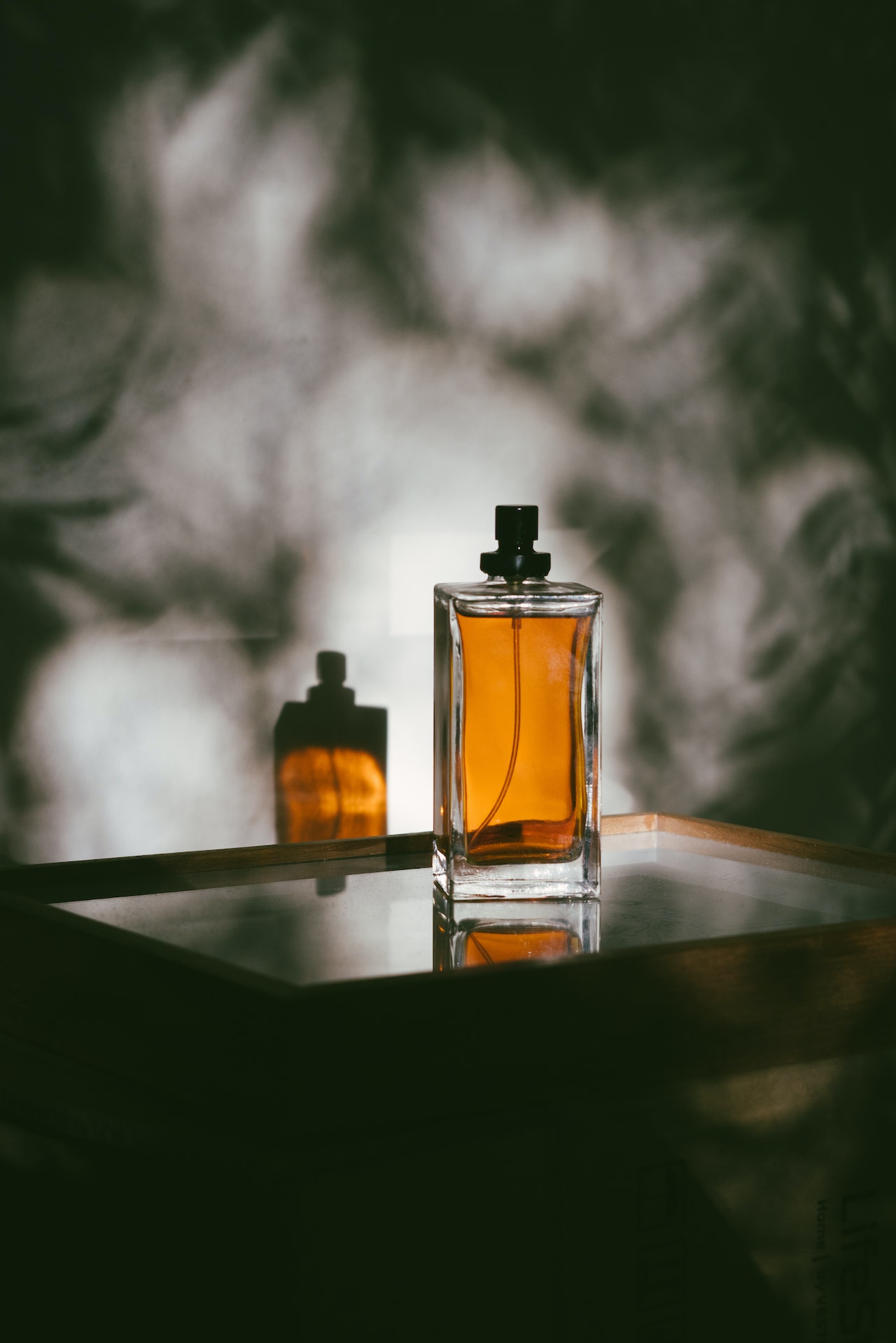 Un flacon de parfum avec son ombre projeté sur de la fumée