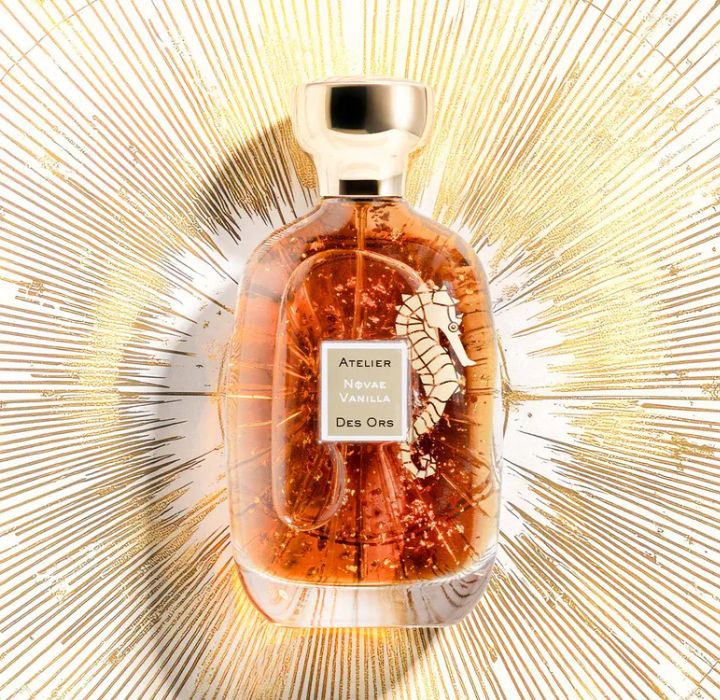 Un élégant flacon de parfum en verre transparent, rempli d'un liquide ambré et ornée de motifs dorés, est mis en valeur contre un fond rayonnant