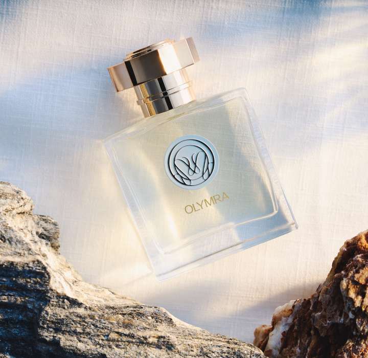 Un flacon de parfum élégant sur un fond de pierre, avec une étiquette dorée et une lumière douce.