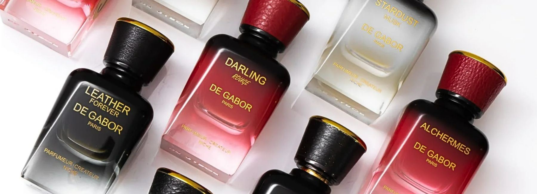 The image shows a collection of perfume bottles from the “De Gabor” brand, sold on the online boutique SCENTISSIME. The bottles have an elegant, sophisticated shape, with gold labels that add a touch of luxury. Perfume colors vary, including dark hues like black and red, as well as lighter shades. Each bottle is topped by a distinctive cap, often in leather, which reinforces the sense of sophistication. The whole presents a beautiful visual harmony, drawing the eye with its meticulous presentation.