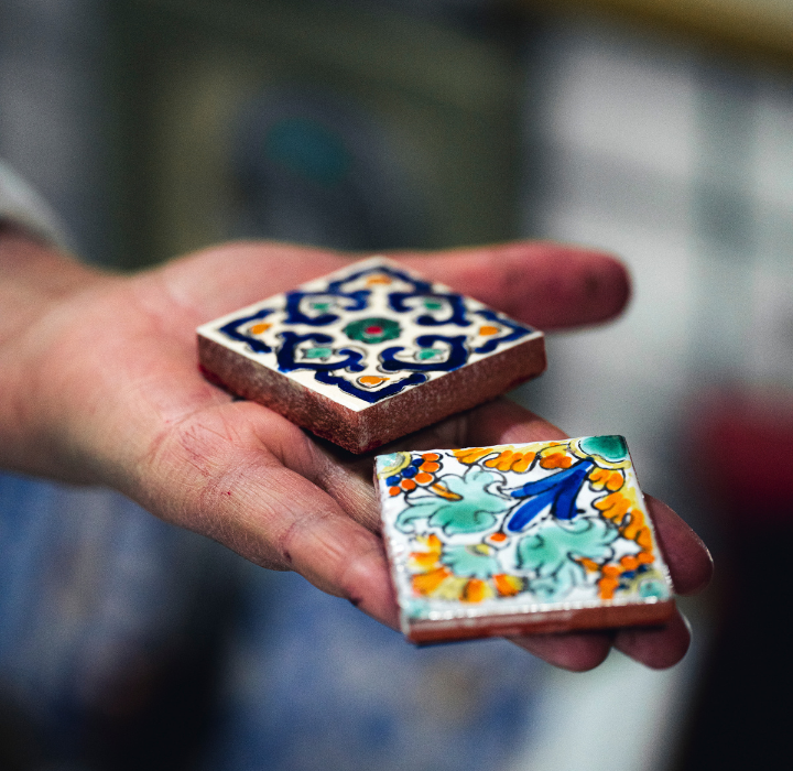 Une main qui présente deux carreaux de mosaïque Zellige - Maison Cataliya