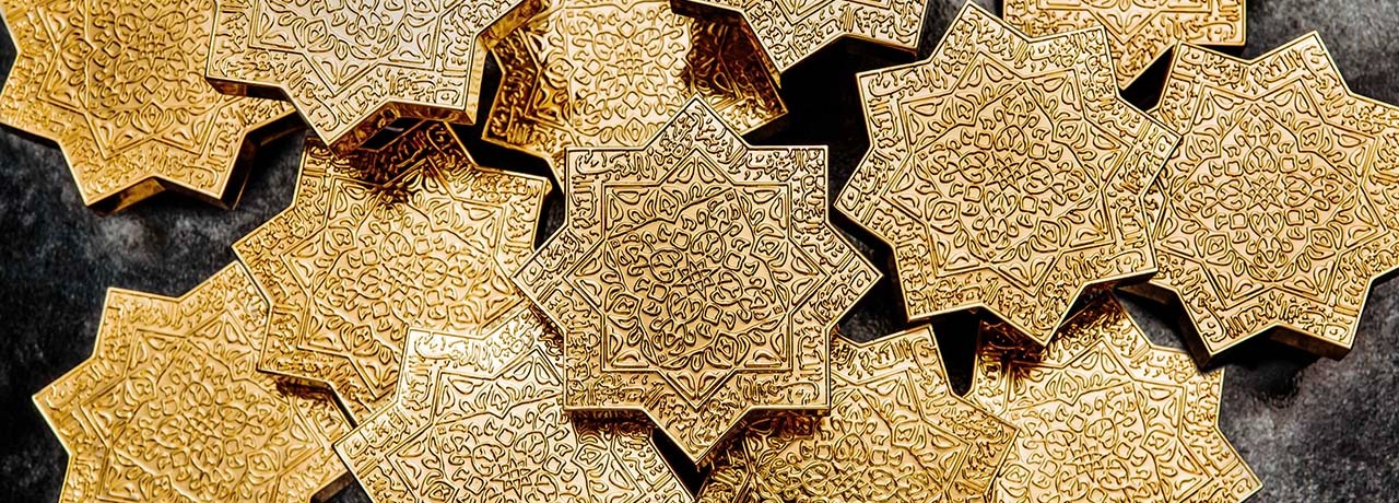 L'image montre un ensemble de coiffes de parfums de niche kAJAL dorés, chacune ayant une forme d'étoile. Les surfaces des coiffes sont ornées de motifs complexes et délicats, illustrant des motifs floraux ou géométriques qui évoquent un style arabe artisanal traditionnel. La lumière se reflète sur les surfaces brillantes, accentuant les détails des gravures et créant des ombres qui ajoutent de la profondeur à l'image. Le fond est sombre, mettant en valeur la brillance dorée des pièces.